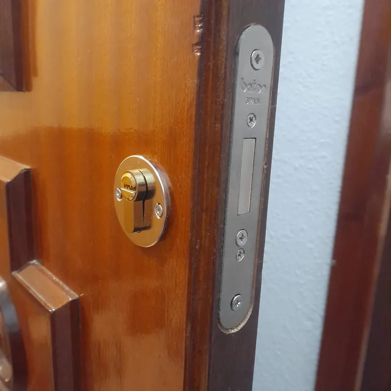 Cerradura Baton con bombín dorado instalada en puerta de madera