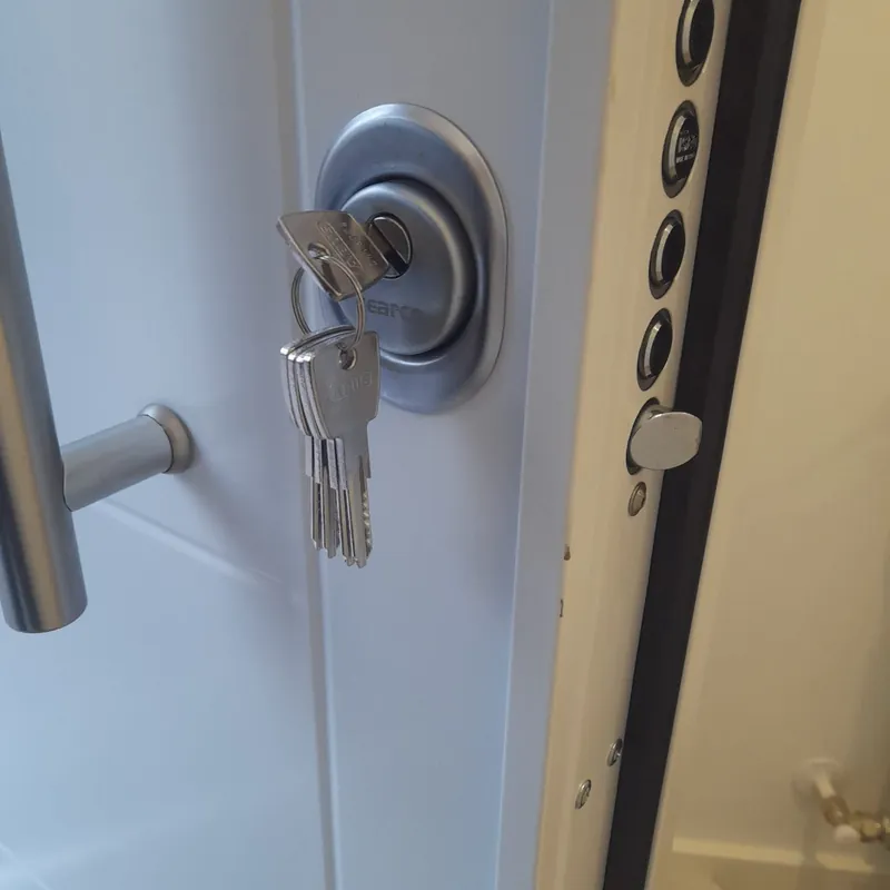 Cilindro ABUS de alta seguridad con escudo protector en puerta blindada blanca