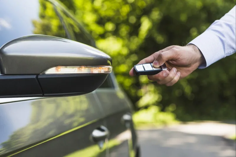 Mano pulsando el mando a distancia de la llave de un coche